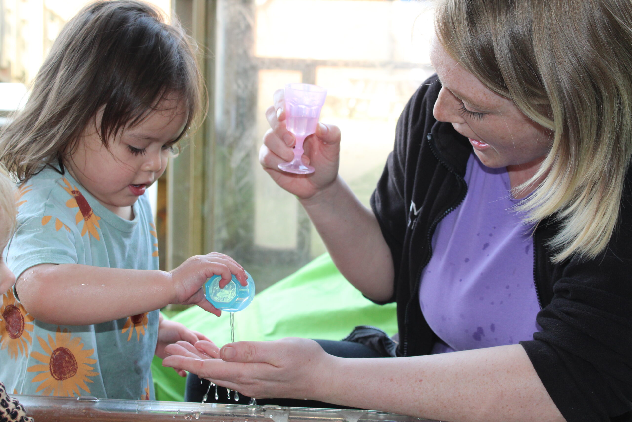 Woolston nursery team member practising pouring with child