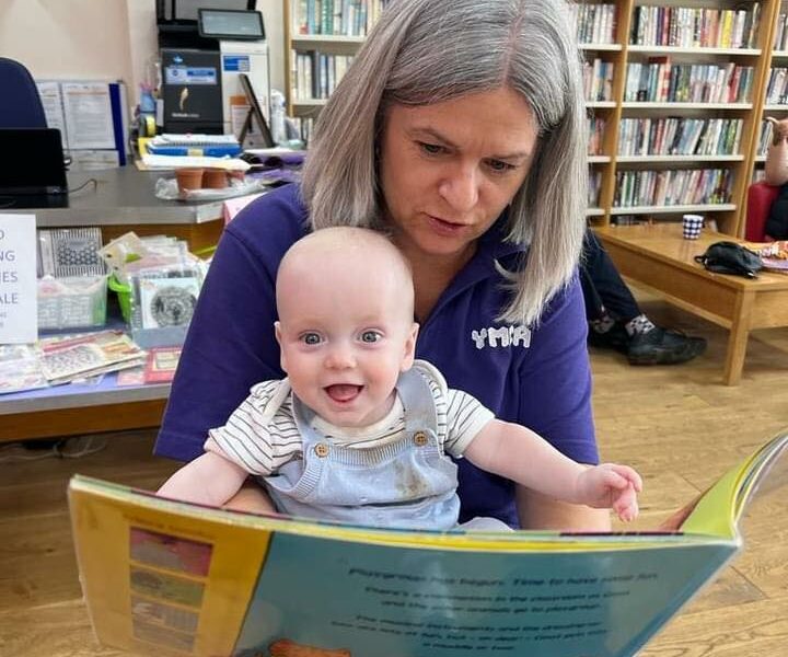 YMCA staff member and baby reading book in Weston Community Library