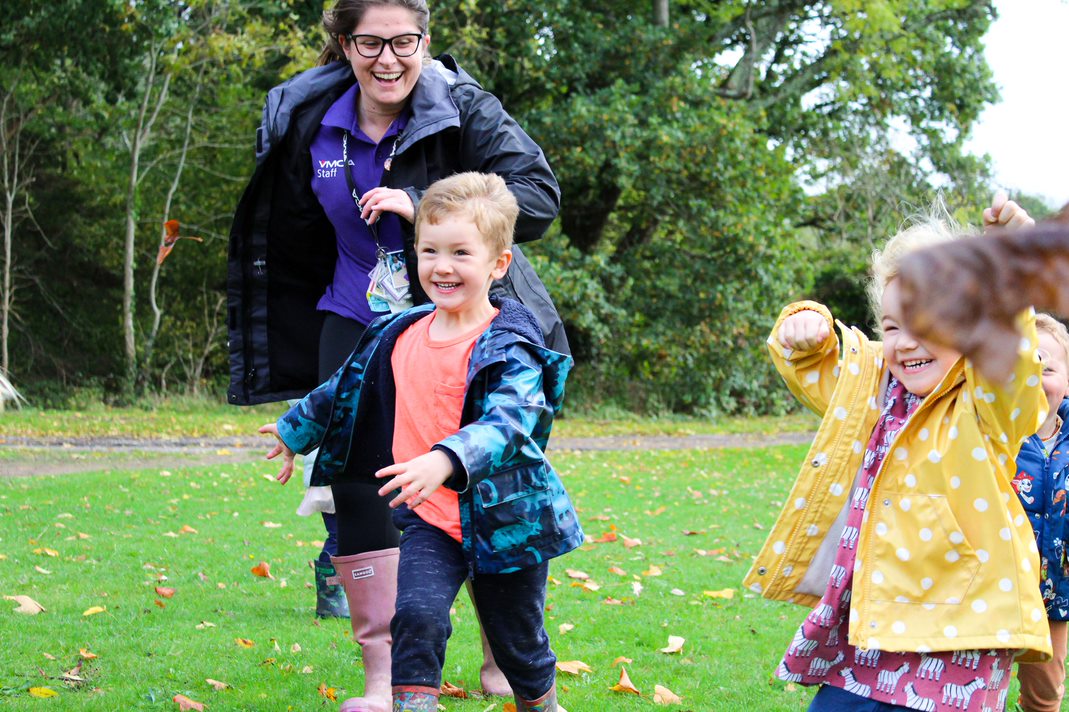 Chlidren and Fairthorne Manor staff member smiling and running outside