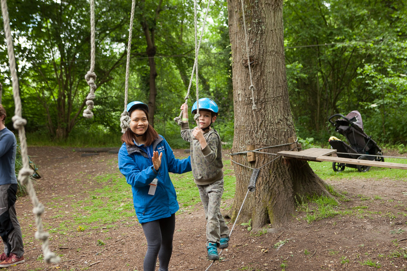 Daycamps instructor helping child cross the low ropes course